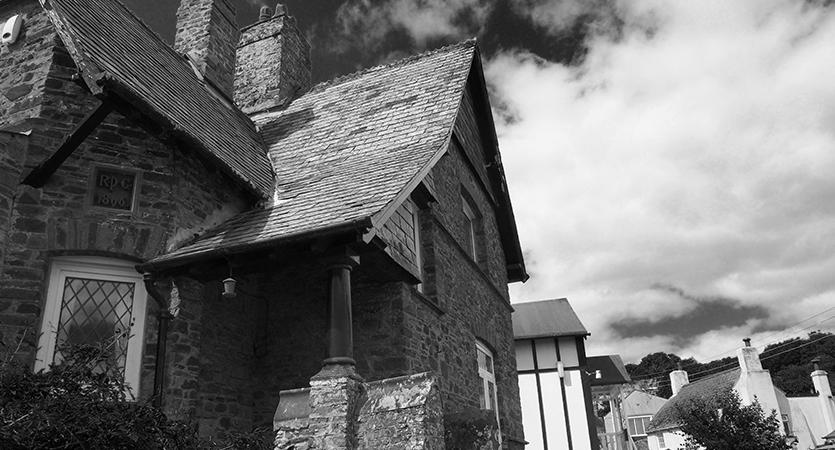 monochrome image of Gothic influenced cottage with dramatic sky behind